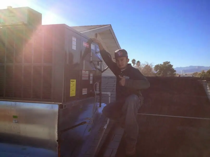 HVAC technician performing AC Tune-Up on a rooftop unit in University